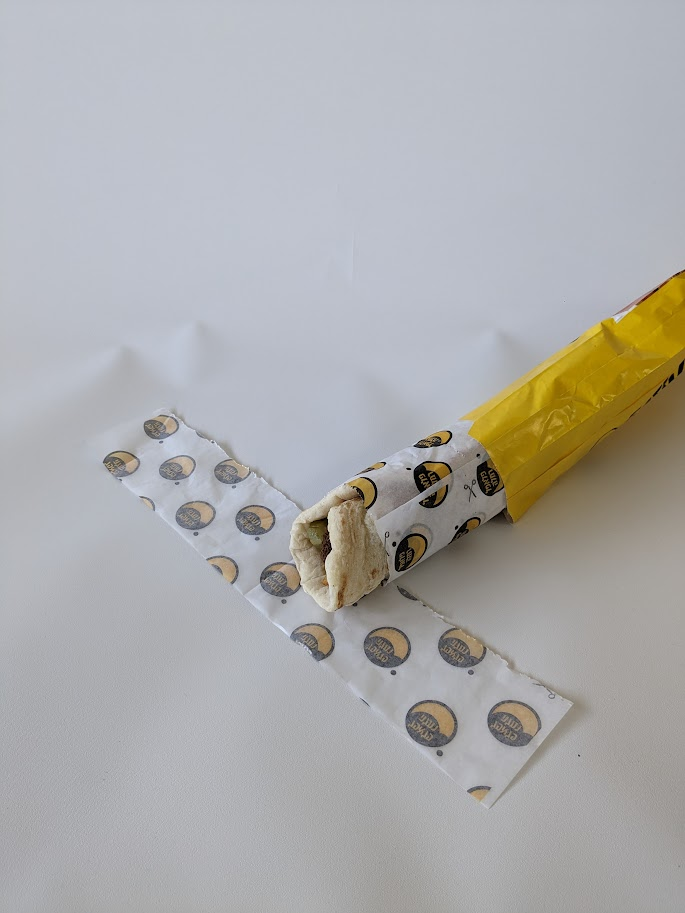 Wrap being unwrapped, with a torn-off perforated strip beside it