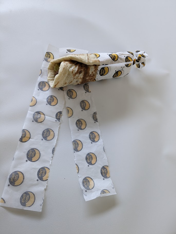 Wrap held with the paper twisted at the bottom and a torn strip beside it