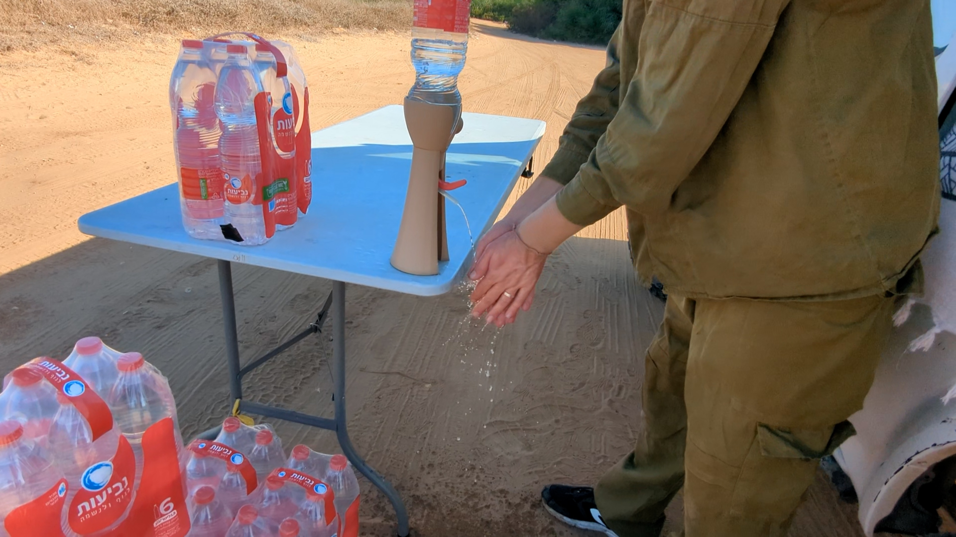 Soldier using the H2GO dispenser to wash hands in the field